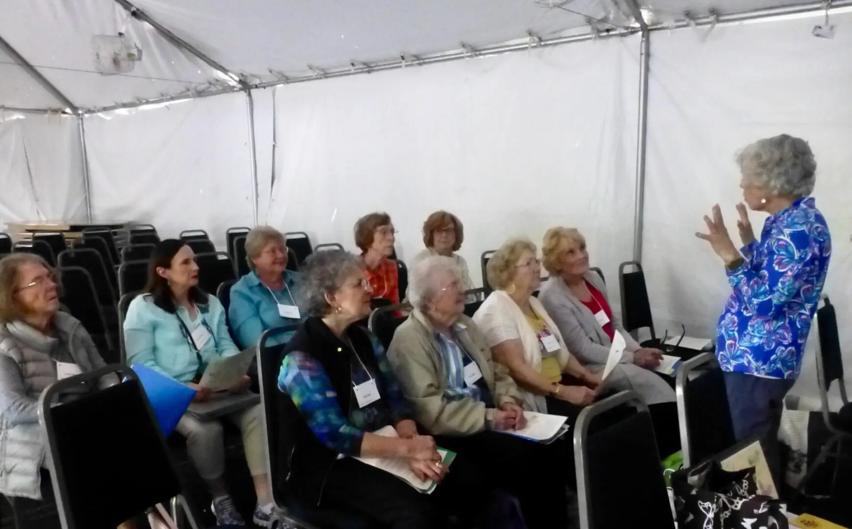 A group of people sitting in chairs under a tent.