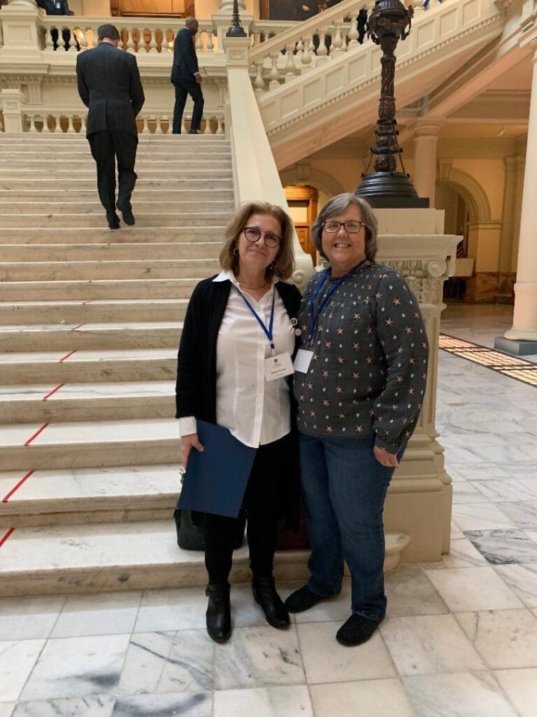 Two women standing on a set of stairs.