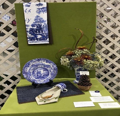 A table with blue and white plates, flowers on it.