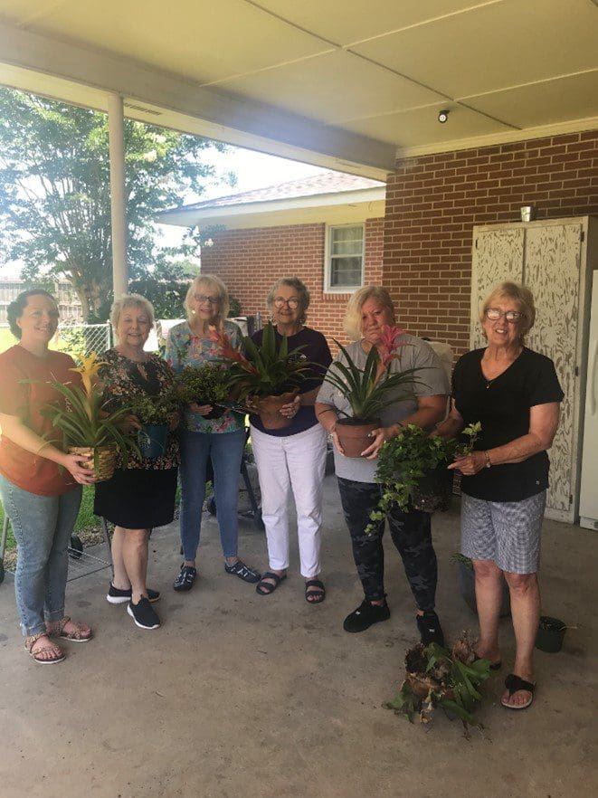 A group of people holding plants in front of a building.