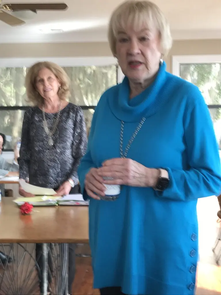 Two women standing in front of a table.