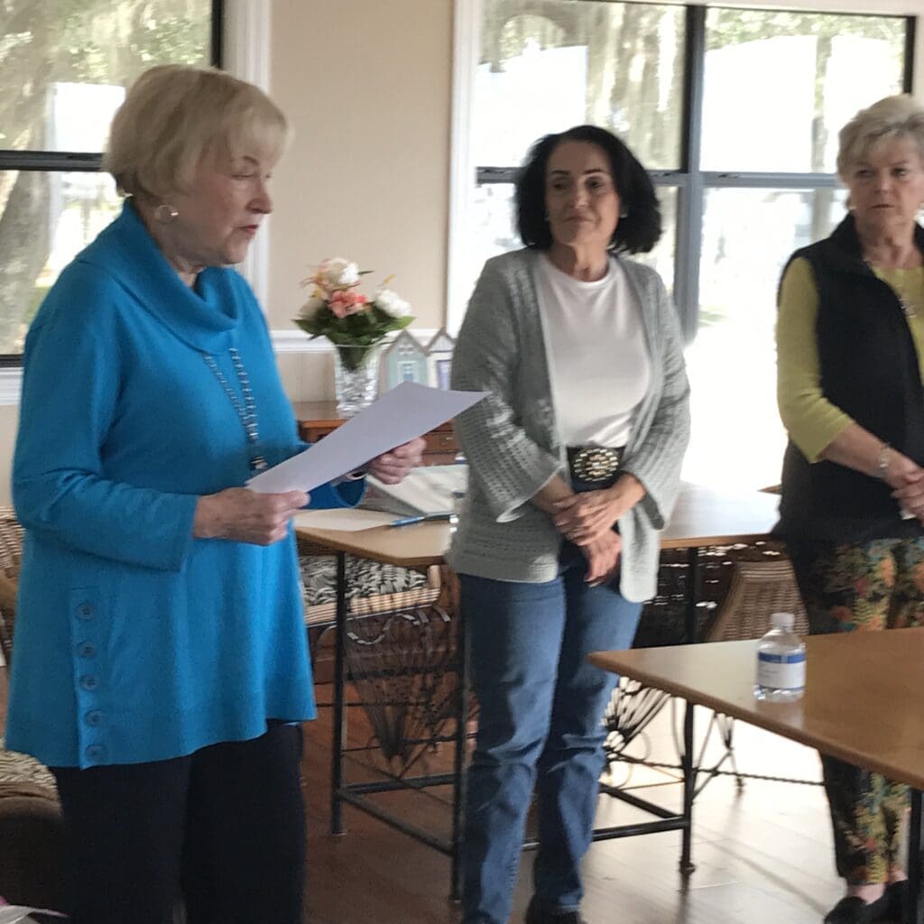 Three women standing in a room with papers.