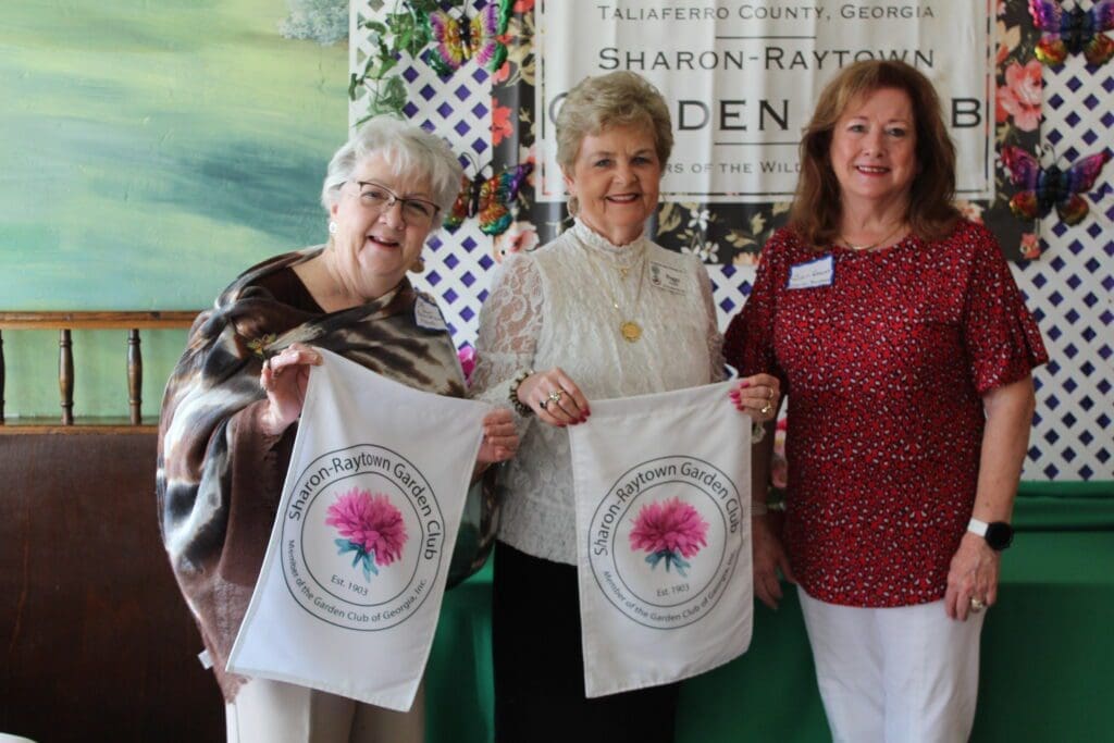 Three women holding up bags of flowers.