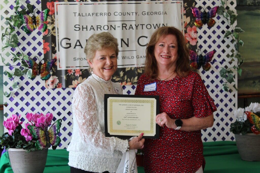 Two women are holding a certificate and smiling.