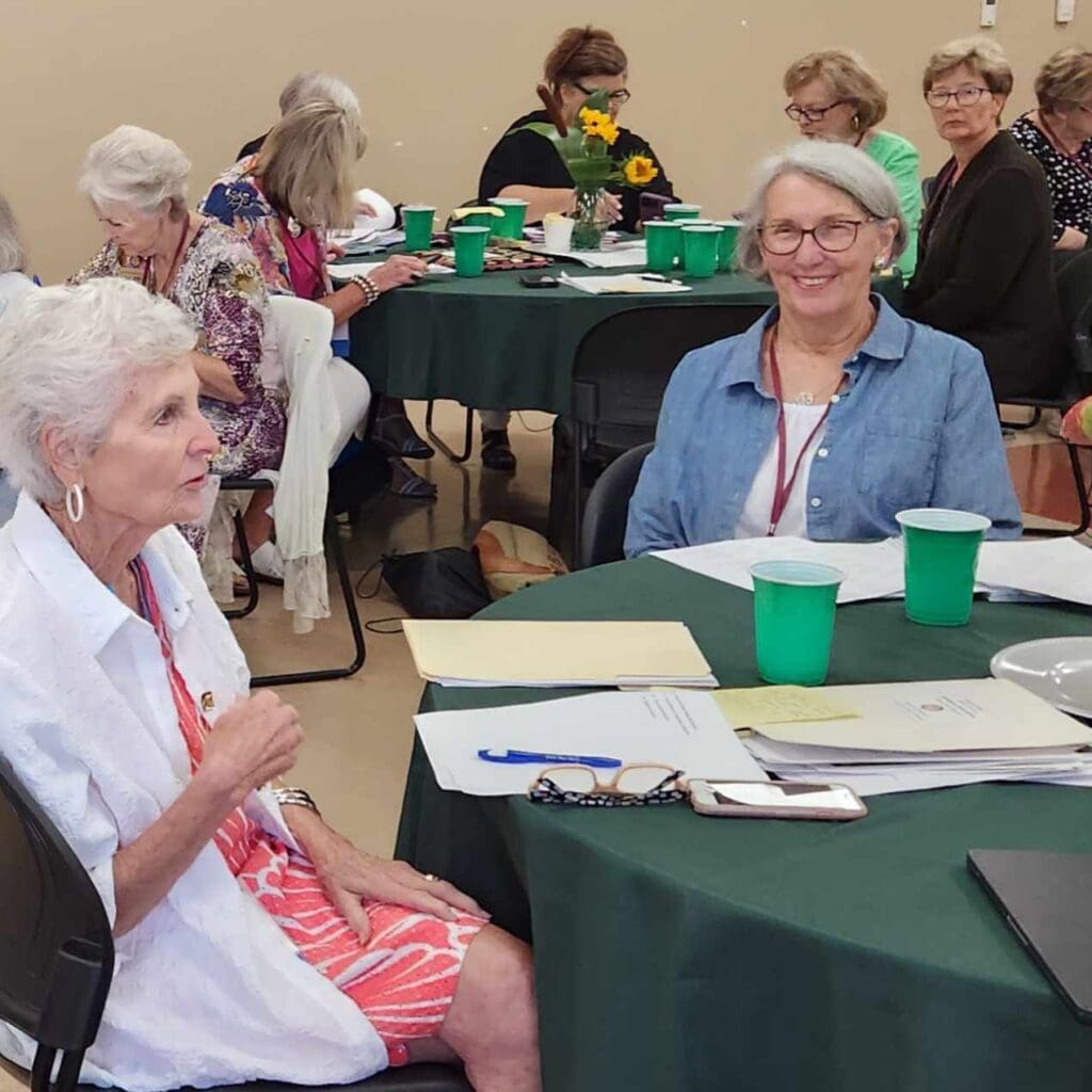 Two women sitting at a table with green cups.