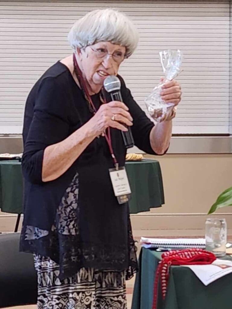 A woman holding up a glass while standing at a microphone.