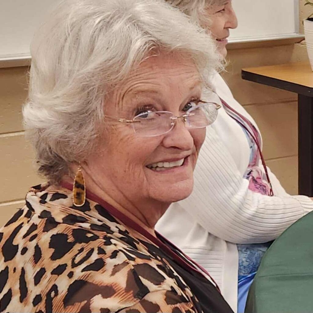 A woman with glasses sitting in front of a table.