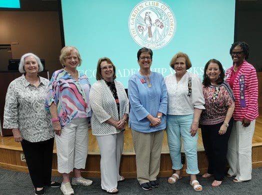 A group of women standing in front of a sign.