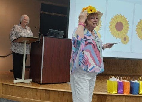 A woman wearing a yellow hat and holding up a balloon.