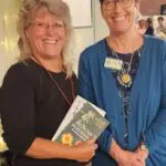 Two women holding a book and smiling for the camera.