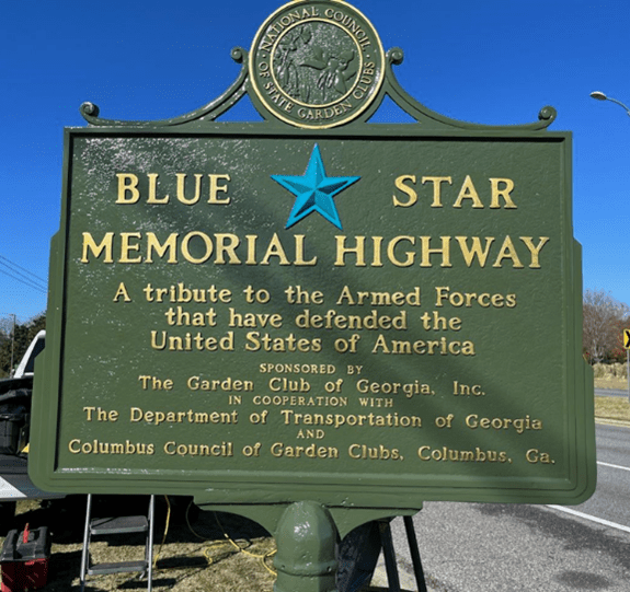 A green sign with the words " blue star memorial highway ".