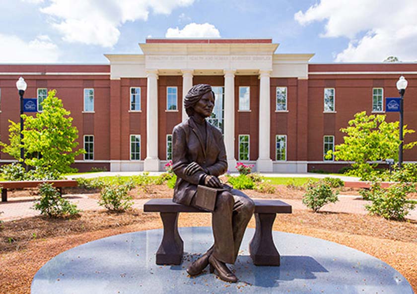 A statue of a woman sitting on top of a bench.