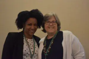 Two women standing next to each other smiling.