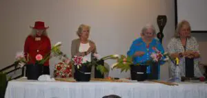 Two women are sitting at a table with plants.