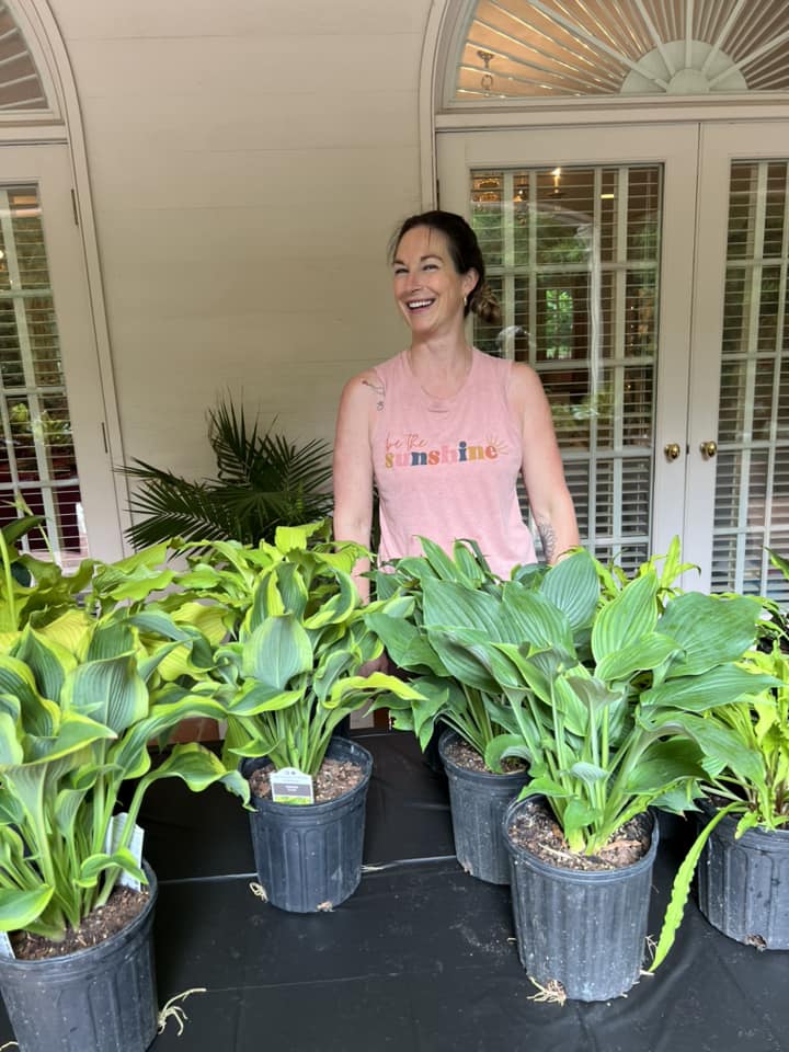 A woman standing next to some large plants.