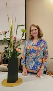 A woman standing in front of a plant.