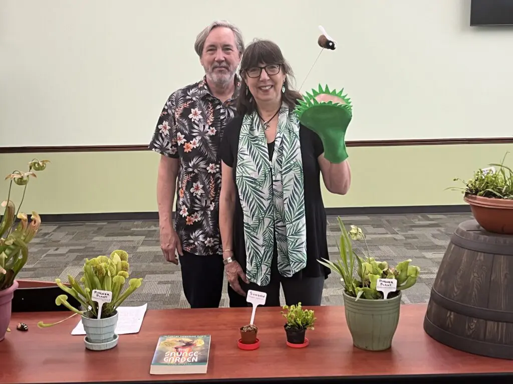 A man and woman standing in front of potted plants.