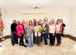 Group of women smiling, holding bouquets indoors