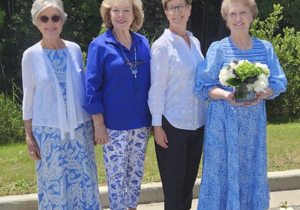 Oleander District Board 8-2024 Four women standing next to each other holding a bouquet of flowers.